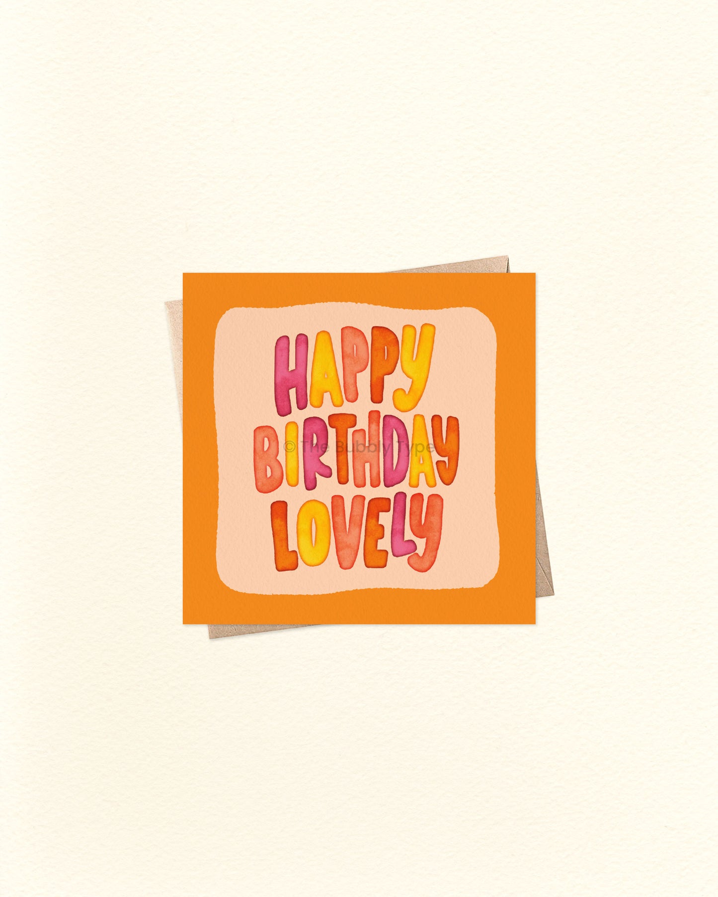 Front of 10cm square birthday card featuring hand-lettered watercolour text that reads “Happy Birthday Lovely” in the centre, surrounded by an orange border and lighter orange background. Paired with a brown kraft envelope. Australian made card by The Bubbly Type – a bright and cheerful birthday greeting for someone special.