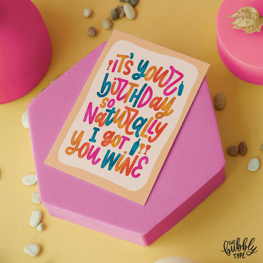 Australian made Happy Birthday Greeting Cards. It's your birthday so naturally I got you wine Unisex birthday card. Front of A6 birthday card featuring a playful hand-lettered message that reads “It’s your birthday so naturally I got you wine” in bold, bright colours with a watercolour finish. The text is in a loopy, cursive style over a pale orange background with a deeper orange border. A cheeky, fun birthday card from The Bubbly Type, shown with a brown kraft envelope.