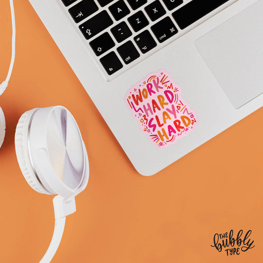 A vibrant vinyl sticker featuring the phrase "Work Hard Slay Hard" in playful hand-lettering, designed in bold pink and orange hues. Perfect for decorating laptops, notebooks, water bottles, and more, this high-quality vinyl sticker is made with durable, self-adhesive vinyl for long-lasting use. Whether you're looking for custom vinyl stickers Australia, shopping for vinyl stickers Officeworks, or exploring options like self-adhesive vinyl Bunnings or Spotlight, this sticker adds a stylish and inspiring tou