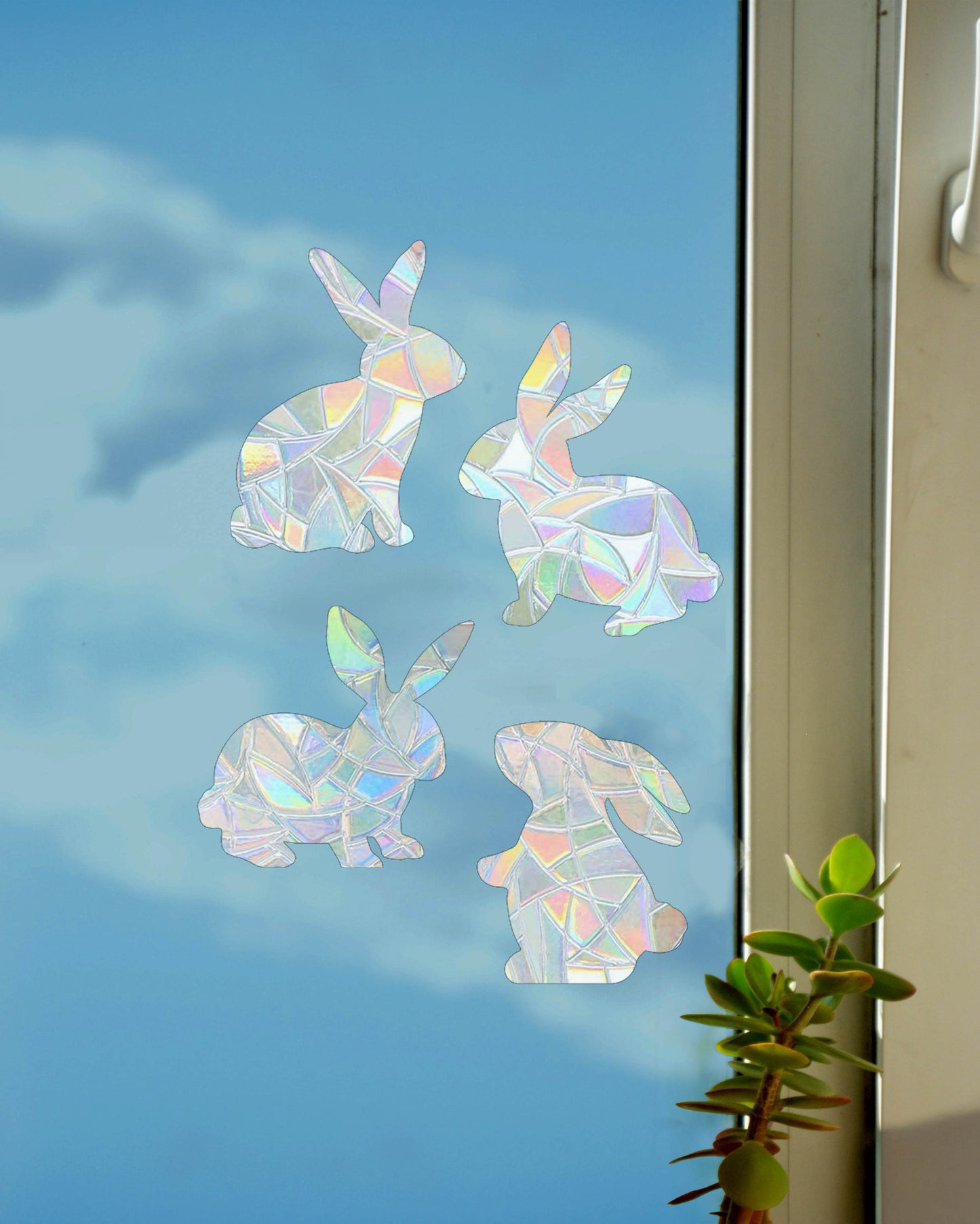 Four bunny rabbit-shaped sun catchers stuck on a window, Australian made rainbow decals that fill the room with light and colour, cute Easter or animal-themed window stickers.