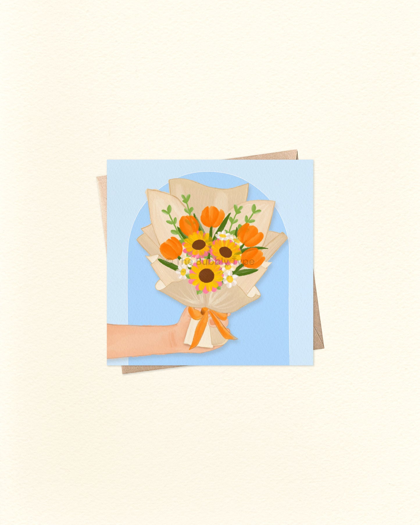 Front of 10cm square greeting card featuring an illustration of a hand holding a bouquet of orange flowers and other vibrant blooms, framed by an arch shape on a blue background. Paired with a brown kraft envelope. Australian made card by The Bubbly Type – a bold and beautiful design perfect for birthdays, thank yous, or just because.