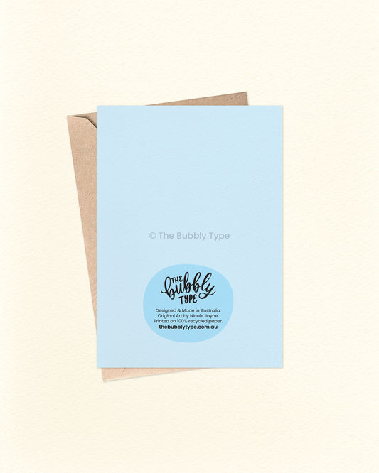 Back of the card with a matching blue background, featuring The Bubbly Type logo and card details. Displayed with a kraft brown envelope. Designed and printed in Australia on sustainable card stock.