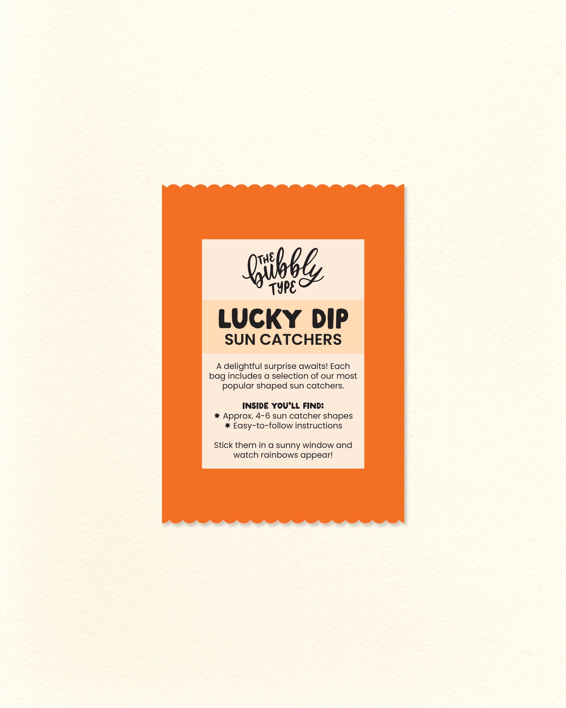 Photo of bright orange scalloped-edge lucky dip bag with a “Sun Catcher Lucky Dip” label listing what's included. Surprise pack of rainbow-making window decals from The Bubbly Type – a joyful gift idea for indecisive shoppers and lovers of light-filled decor.