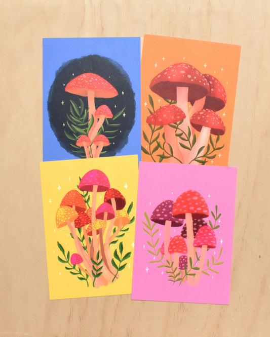 Four colourful cards with mushroom illustration postcards on a wooden surface