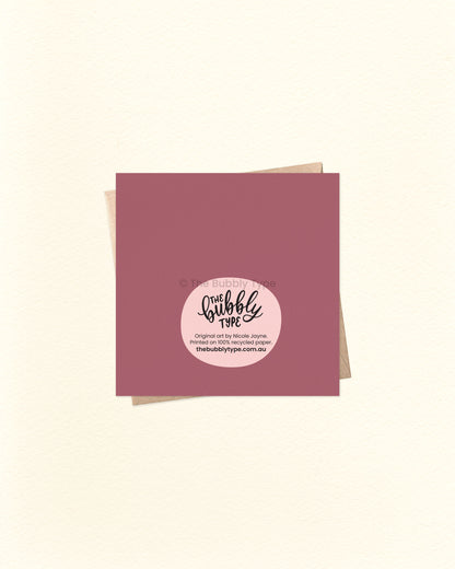 Back of the card with a deep purple background, showing The Bubbly Type logo and print details. Shown with a kraft brown envelope. Designed and printed in Australia using eco-friendly materials.