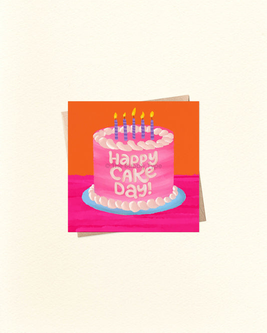 Small square birthday card featuring colourful cake illustration and ‘Happy Cake Day’ message, photographed on top of a brown kraft envelope. Buy fun birthday cards in Australia for cake lovers and party people.