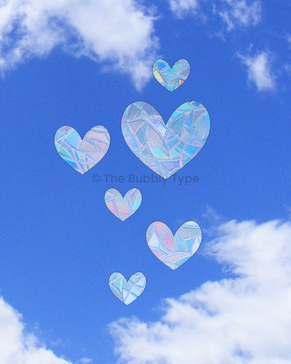 Six heart-shaped sun catchers in various sizes stuck on a window, Australian made rainbow decals spreading love and colour, cute heart window stickers for romantic or playful home decor.