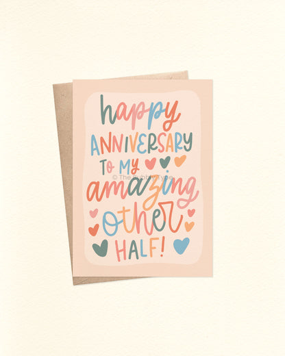 Front of A6 anniversary card featuring whimsical cursive hand-lettering that reads: “happy anniversary to my amazing other half.” Lettering appears in soft neutral tones including dusky sage green, pale pink, peachy orange, and powder blue over a cream background. Shown with a brown kraft envelope.