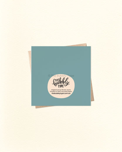 Back of the card with a blue background, displaying The Bubbly Type logo and print details. Shown with a kraft brown envelope. Designed and printed in Australia using eco-friendly cardstock.
