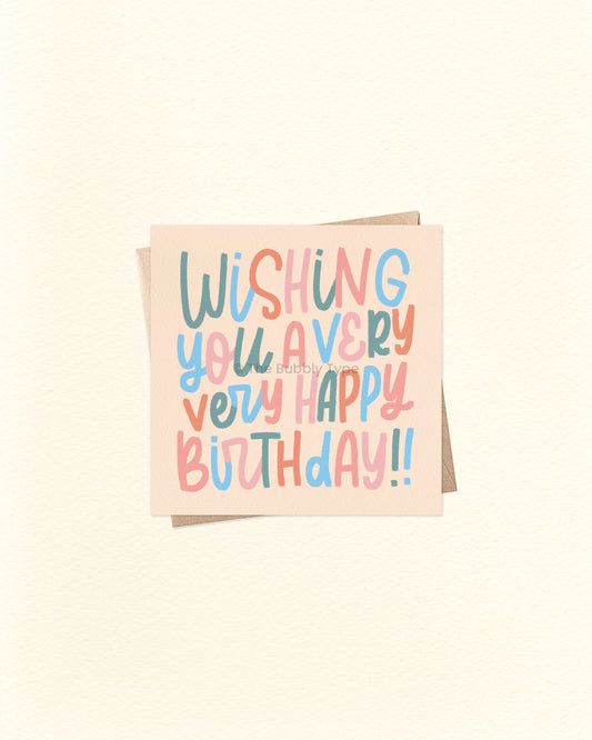 Front of 10cm square birthday card with hand-lettered text reading “Wishing You a Very Very Happy Birthday!!” in whimsical lettering. Features a colour palette of green, blue, orange, and pale pink on a soft orangey beige background. Paired with a brown kraft envelope. A fun and playful birthday card by The Bubbly Type – proudly Australian made.
