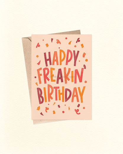 Front of A6 birthday card featuring bold blocky hand-lettered text that reads “Happy Freakin' Birthday” surrounded by colourful confetti. The design uses warm, bright colours like orange, yellow, warm purple, and cream. A fun and cheeky birthday card from The Bubbly Type, perfect for friends or anyone who loves bold vibes. Shown with a brown kraft envelope.