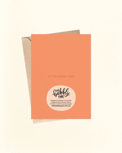 Back of the card with a bold orange background, featuring The Bubbly Type logo and card details. Shown with a kraft brown envelope. Proudly designed and printed in Australia on sustainable cardstock.