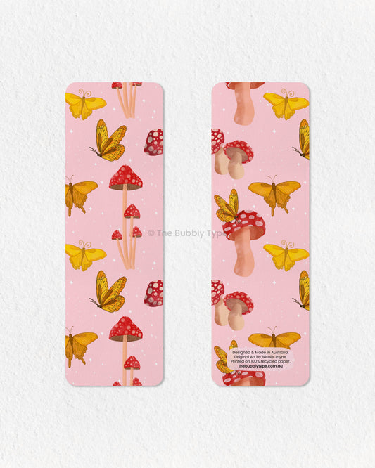 Whimsical Butterfly & Mushroom Bookmark – Add a touch of magic to your reading with this enchanting pink bookmark, featuring a flurry of yellow butterflies dancing among red-capped mushrooms. With its fairy tale-inspired design and warm, whimsical colour palette, this bookmark is perfect for lovers of cottagecore, fantasy, and nature’s little wonders. Printed on 100% recycled paper, it’s double-sided, high-quality, and finished with rounded corners for a polished look. A dreamy gift for bookworms!