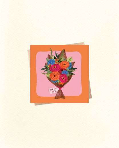 Front of 10cm square everyday greeting card featuring a bouquet of orange, pink, and blue flowers with green foliage, wrapped in brown paper with a tag that reads “Just For You.” Set on a pink background with an orange border. Paired with a brown kraft envelope. A versatile Australian made card by The Bubbly Type – perfect for thank yous, thinking of you, or gift-giving occasions.