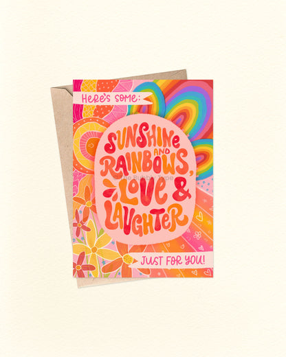 Front of A6 greeting card with the hand-lettered message: “Here’s some: Sunshine and rainbows, love & laughter just for you.” The background is filled with a vibrant, hand-drawn design of rainbows, flowers, bursts, and zentangle-style line patterns in a retro, hippy chic vibe. A joyful and uplifting card, shown with a brown kraft envelope.