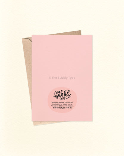 Back of the card with a matching pink background, featuring The Bubbly Type logo and card details. Displayed with a kraft brown envelope. Printed in Australia using eco-friendly materials.