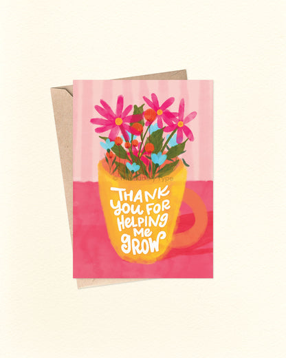 Front of A6 greeting card featuring a whimsical hand-lettered message on a yellow mug with an orange handle that reads, “Thank you for helping me grow.” The mug is filled with a vibrant watercolour bouquet of pink, orange, and blue flowers, set against a pink background. A heartfelt Australian made card by The Bubbly Type – perfect for teachers, mentors, parents, or anyone who’s made a difference. Shown with a brown kraft envelope.