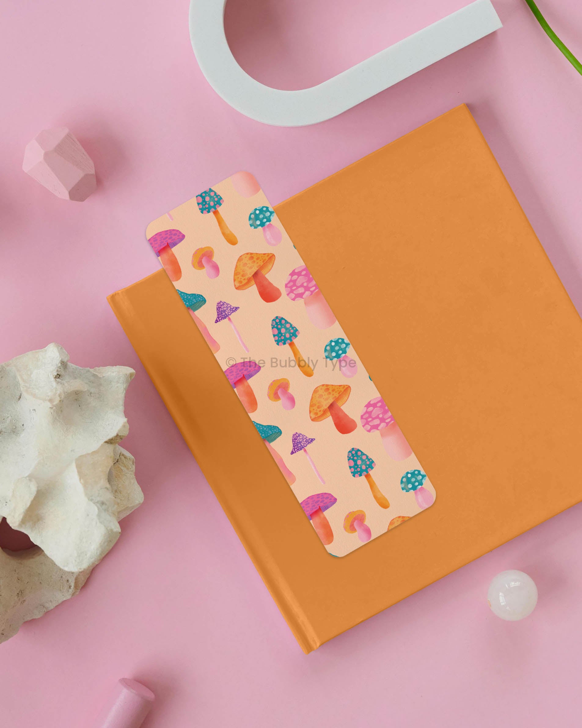 Colourful Mushroom Fantasy Bookmark – Add a twist to your reading with this psychedelic mushroom bookmark, featuring a kaleidoscope of fungi in rainbow hues against a soft pale orange background. With a design that’s equal parts funky, whimsical, and eye-catching, this double-sided bookmark is perfect for fans of retro aesthetics and mystical forests. Made from 100% recycled paper, it’s eco-friendly, vibrant, and finished with rounded corners for a polished look. A fun and quirky gift for bookish friends!
