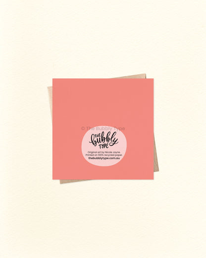 Back of the card with a vibrant peach-pink background, featuring The Bubbly Type logo and print details. Printed sustainably in Australia. Shown with a kraft brown envelope.