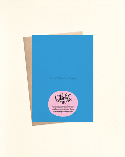 The back of the A6 card features a solid mid-blue background with The Bubbly Type logo and card details printed at the bottom. Shown with a kraft brown envelope. Printed on 100% recycled paper in Australia.