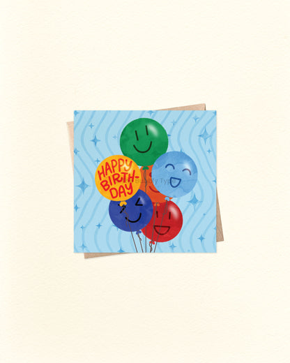 Front of 10cm square birthday card featuring a playful illustration of birthday balloons in green, blue, yellow, dark blue, and red. Each balloon has a different smiley face, except the yellow one which reads “Happy Birthday.” Set on a cheerful blue background with squiggle lines and star accents. Paired with a brown kraft envelope. A fun, feel-good birthday card by The Bubbly Type – made in Australia. Great for boys' birthdays!
