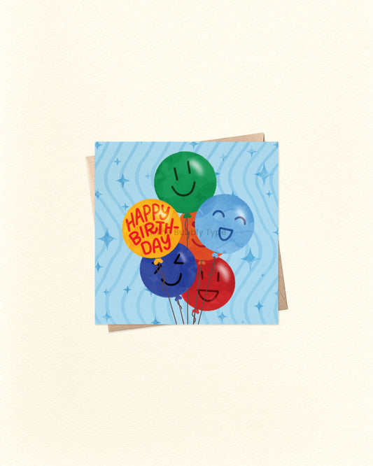 Front of 10cm square birthday card featuring a playful illustration of birthday balloons in green, blue, yellow, dark blue, and red. Each balloon has a different smiley face, except the yellow one which reads “Happy Birthday.” Set on a cheerful blue background with squiggle lines and star accents. Paired with a brown kraft envelope. A fun, feel-good birthday card by The Bubbly Type – made in Australia. Great for boys' birthdays!