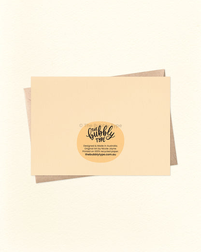 Back of the card with a matching pale yellow cream background, showing The Bubbly Type logo and card details. Displayed with a kraft brown envelope. Proudly printed in Australia using sustainable materials.