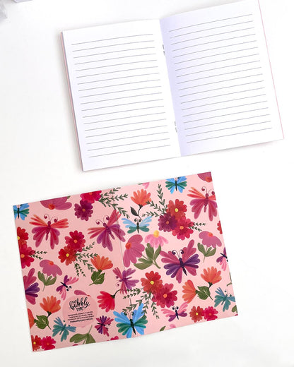 Two A5 Butterfly Garden notebooks. The top notebook is open to the middle, displaying white pages with faint grey lines. The bottom notebook is open and facing down to reveal the back cover, which continues the front’s floral and butterfly pattern. The back also features The Bubbly Type logo and print details at the bottom.