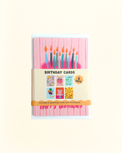 A 6-pack of birthday cards in a clear plastic sleeve with a paper band label. The front card features a pink striped background with colourful birthday candles and a pink 'Happy Birthday' banner.