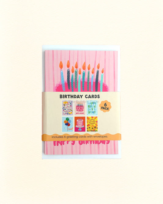 A 6-pack of birthday cards in a clear plastic sleeve with a paper band label. The front card features a pink striped background with colourful birthday candles and a pink 'Happy Birthday' banner.
