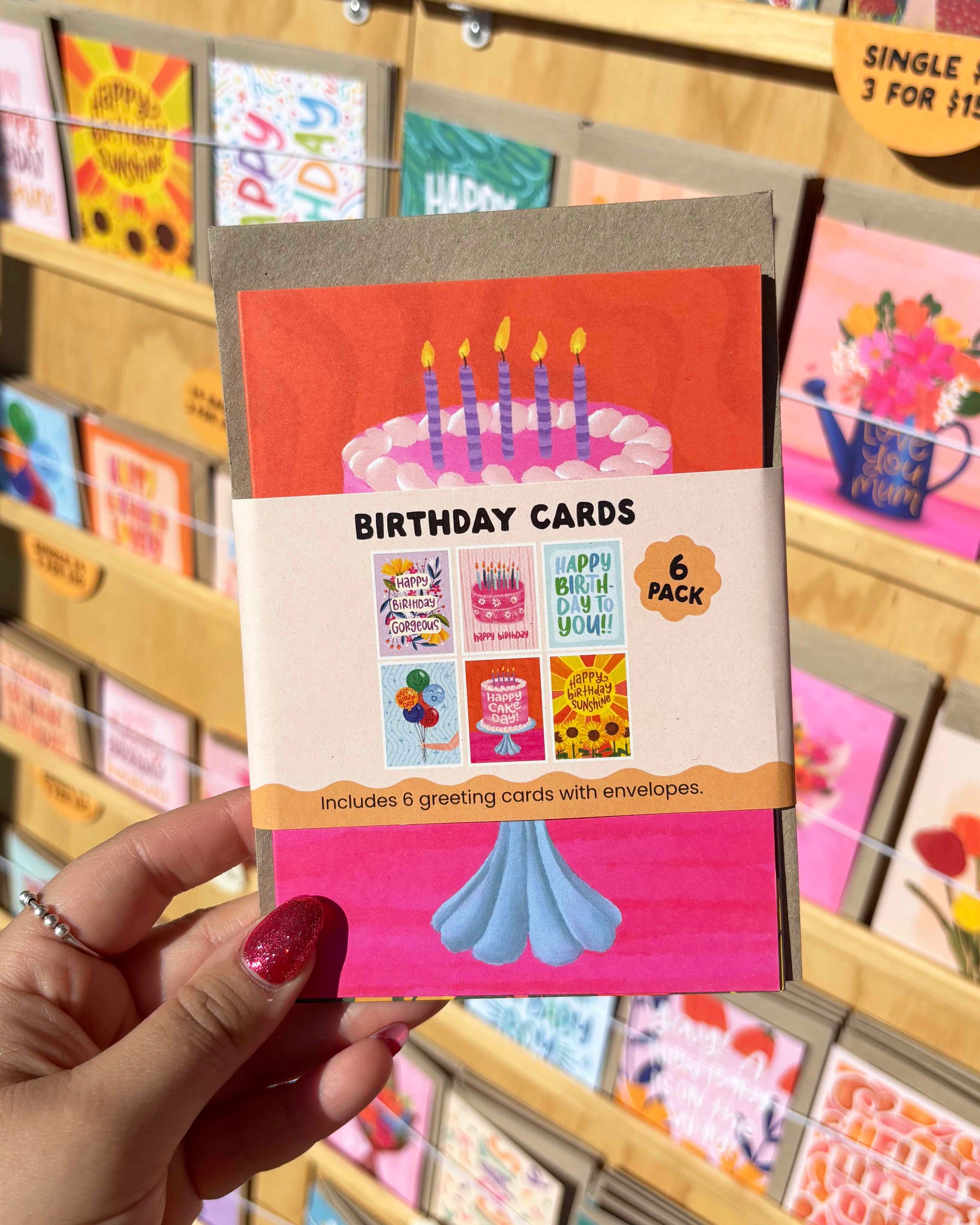 Pack of birthday cards held by a hand with a blurred store display in the background