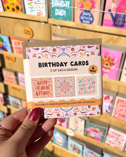 Pack of birthday cards held by a hand with a blurred store background