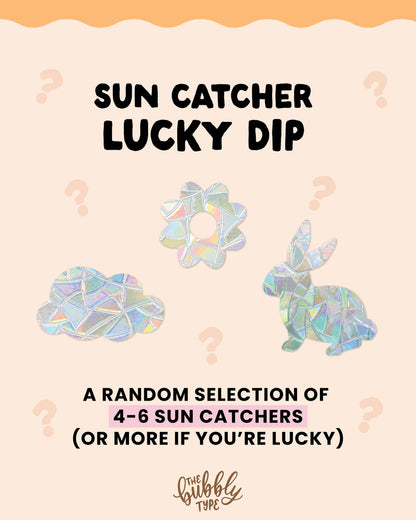 Main product image with text overlay: “Sun Catcher Lucky Dip – a random selection of 3–4 sun catchers (or more if you're lucky)”. Features sample shapes including cloud, flower, and bunny rabbit. Fun and colourful mystery window decals by The Bubbly Type – perfect for rainbow lovers, kids’ rooms, and sunny spaces.