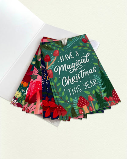 Open packaging of Christmas gift tag set with tags fanned out inside. Colourful, unique designs with included string—perfect for easy holiday gifting.