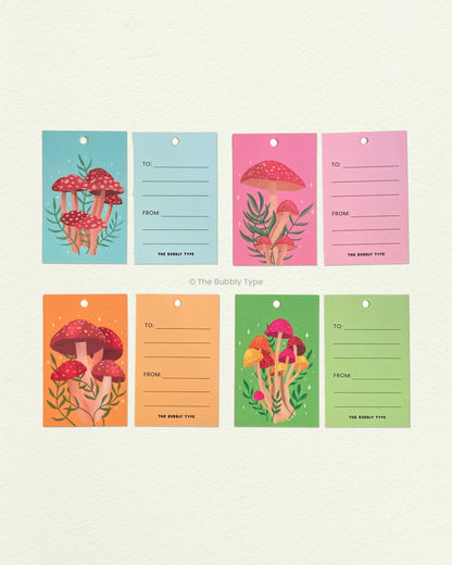 All four mushroom gift tags laid flat showing front and back. Features botanical and forest-inspired illustrations. Ideal for earthy, thoughtful gifting.