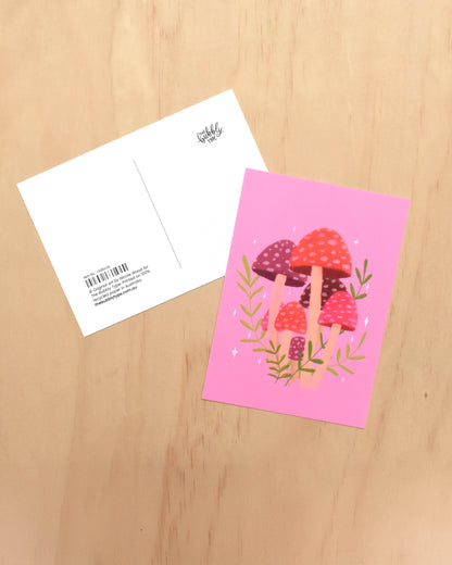 Pink greeting card with mushroom design on a wooden surface
