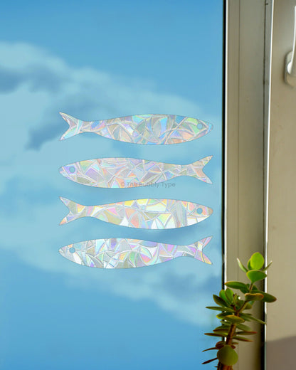 Rainbow making sun catchers in fish shapes on a window with a blue sky background