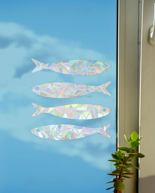Rainbow making sun catchers in fish shapes on a window with a blue sky background