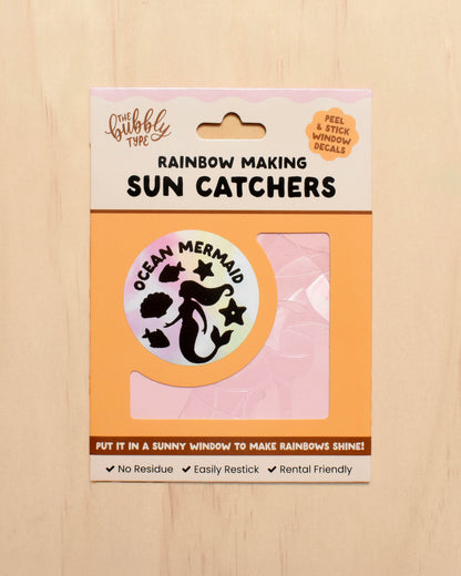 Packaging of rainbow-making sun catchers with a mermaid design on a wooden surface