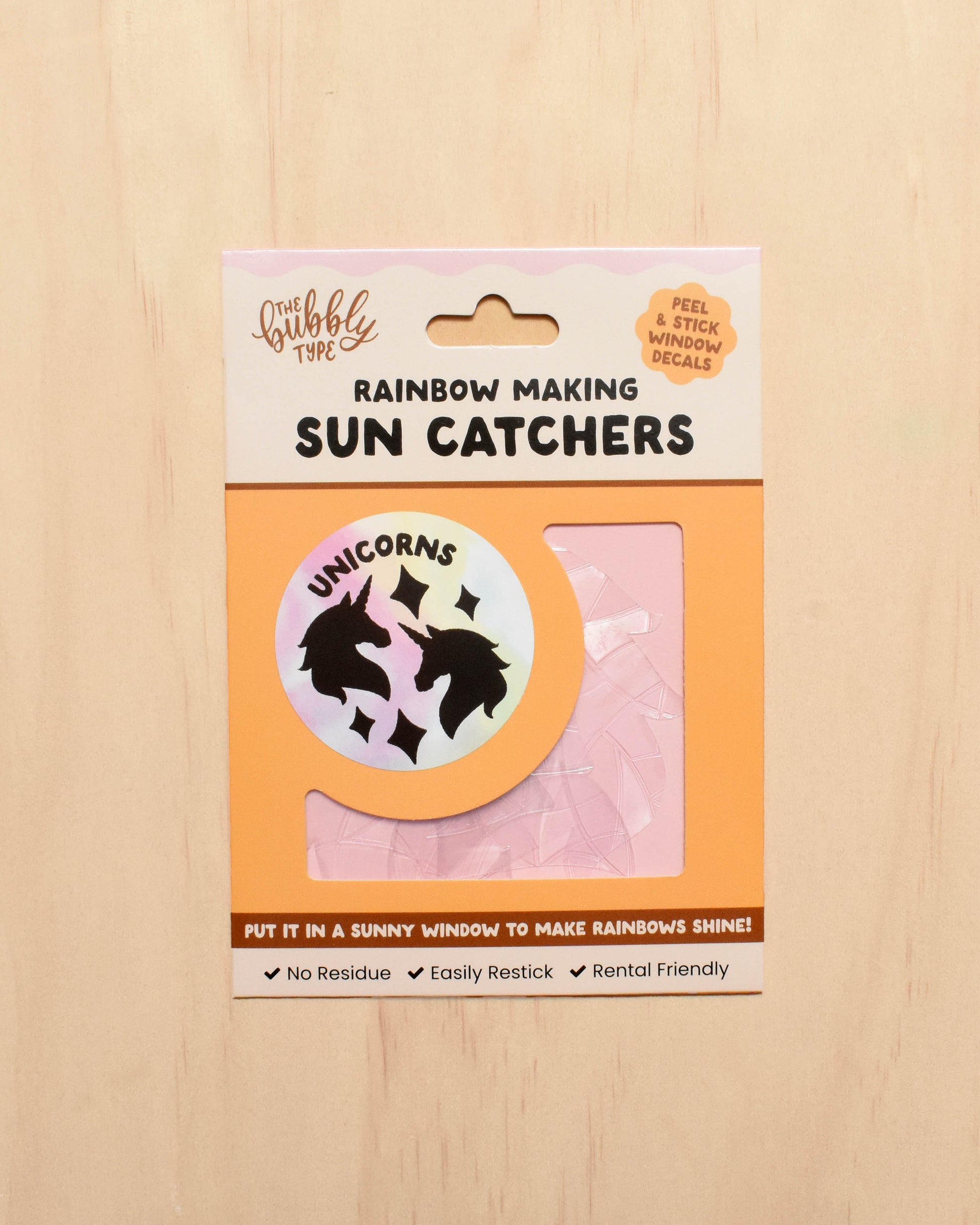 Packaging of sun catchers with a unicorn design on a wooden surface