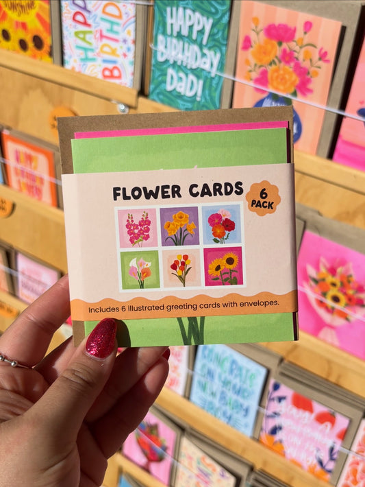 6-pack of flower-themed greeting cards held by a hand with colorful cards in the background.