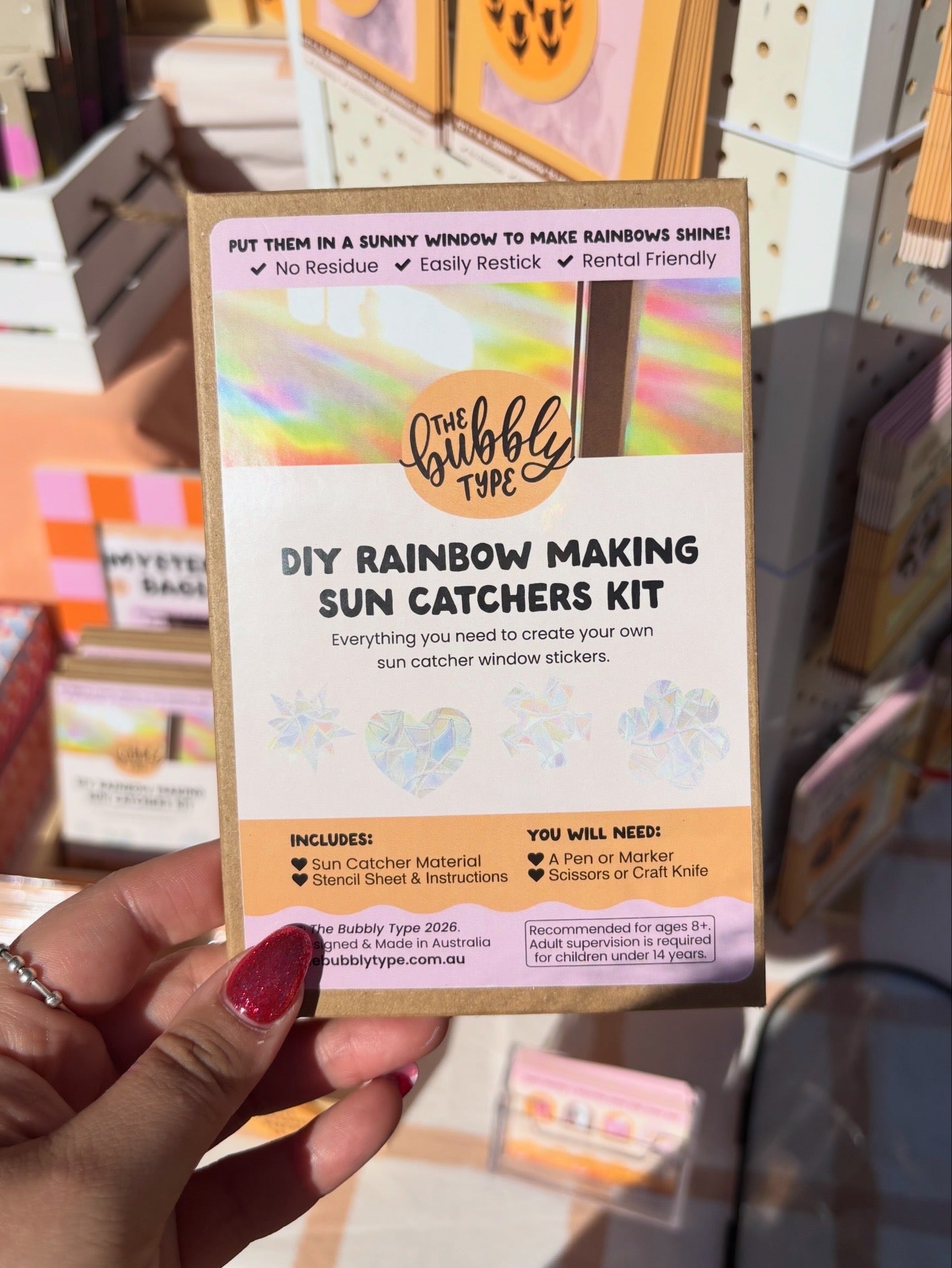DIY Rainbow Making Sun Catchers Kit packaging held by a hand with red nail polish.