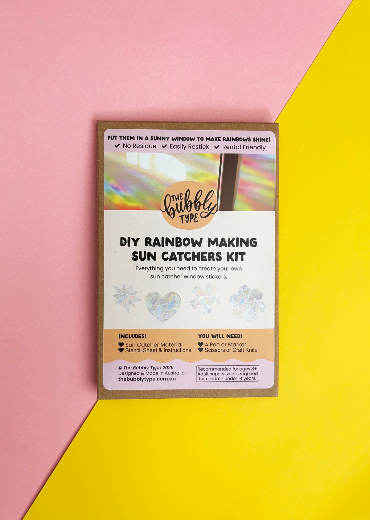 A DIY Rainbow Making Sun Catchers Kit by The Bubble Type, shown in its packaging box against a diagonally split pink and yellow background.