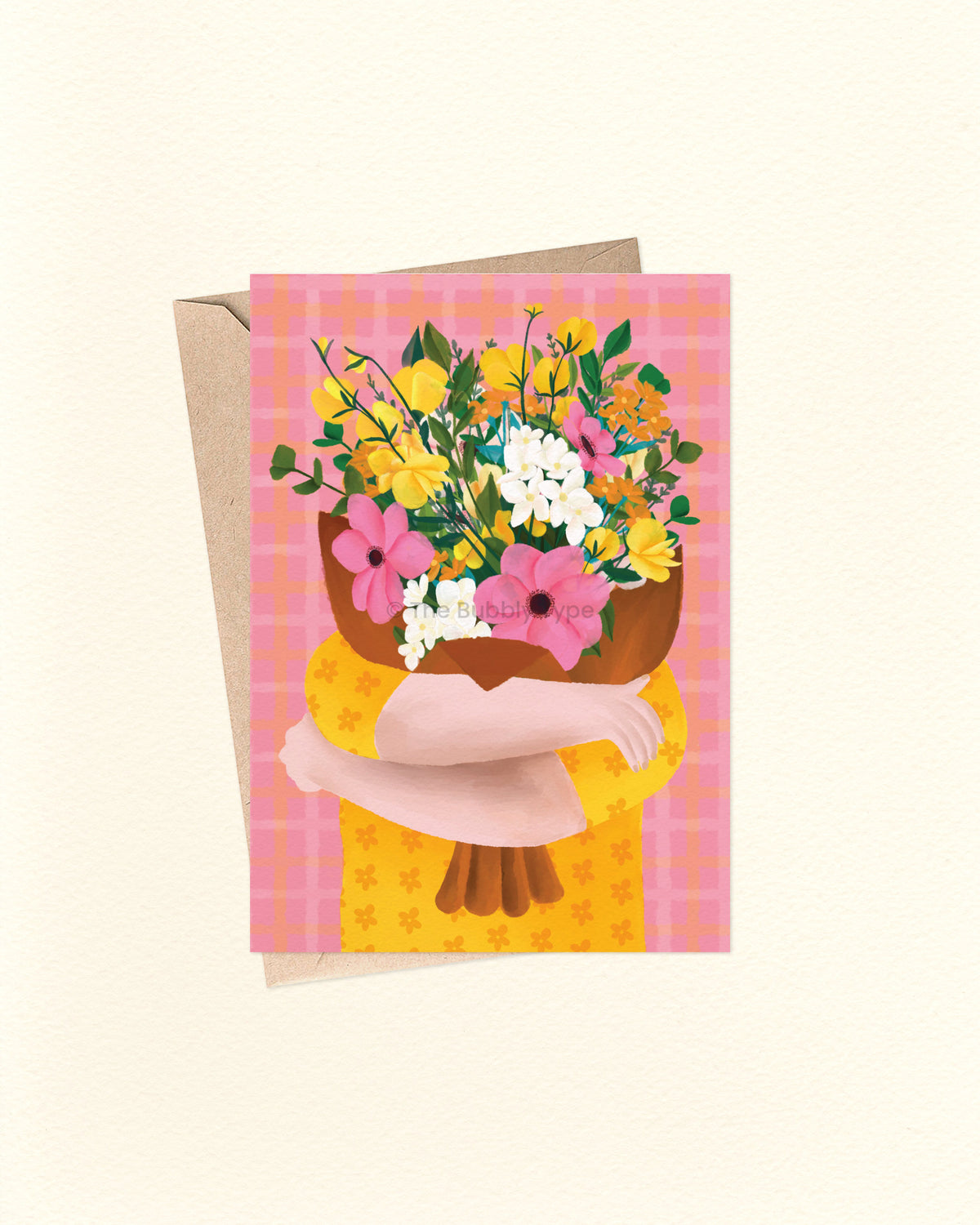 A square greeting card with a kraft envelope, featuring an illustration of a person hugging a large bouquet of yellow, pink, and white flowers against a pink plaid background.