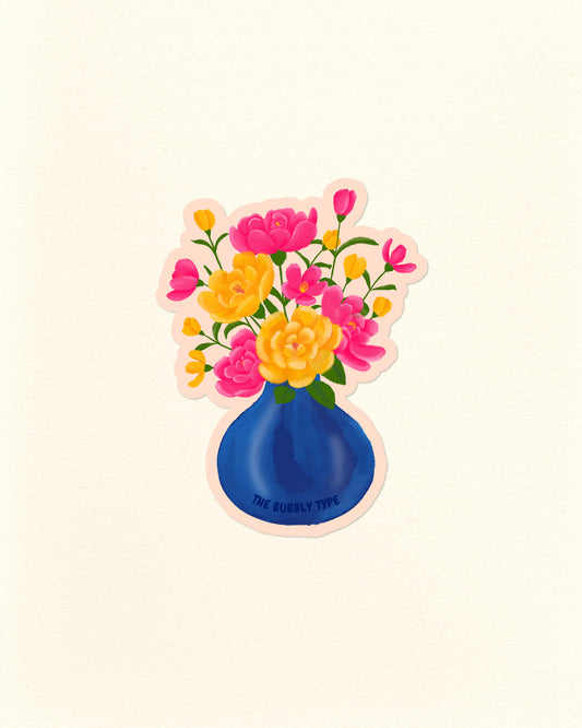 A die-cut sticker featuring a blue vase filled with pink and yellow flowers, shown on a plain off-white background. The sticker has a light pink border and the text 'THE BUBBLY TYPE' printed on the blue vase.