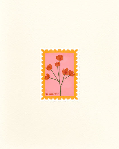 A vinyl die cut sticker of a postage stamp featuring orange Californian poppies flowers on a pink background with a yellow-orange border, centred on a warm off-white textured backdrop. Small text at the bottom reads 'THE BUBBLY TYPE'.