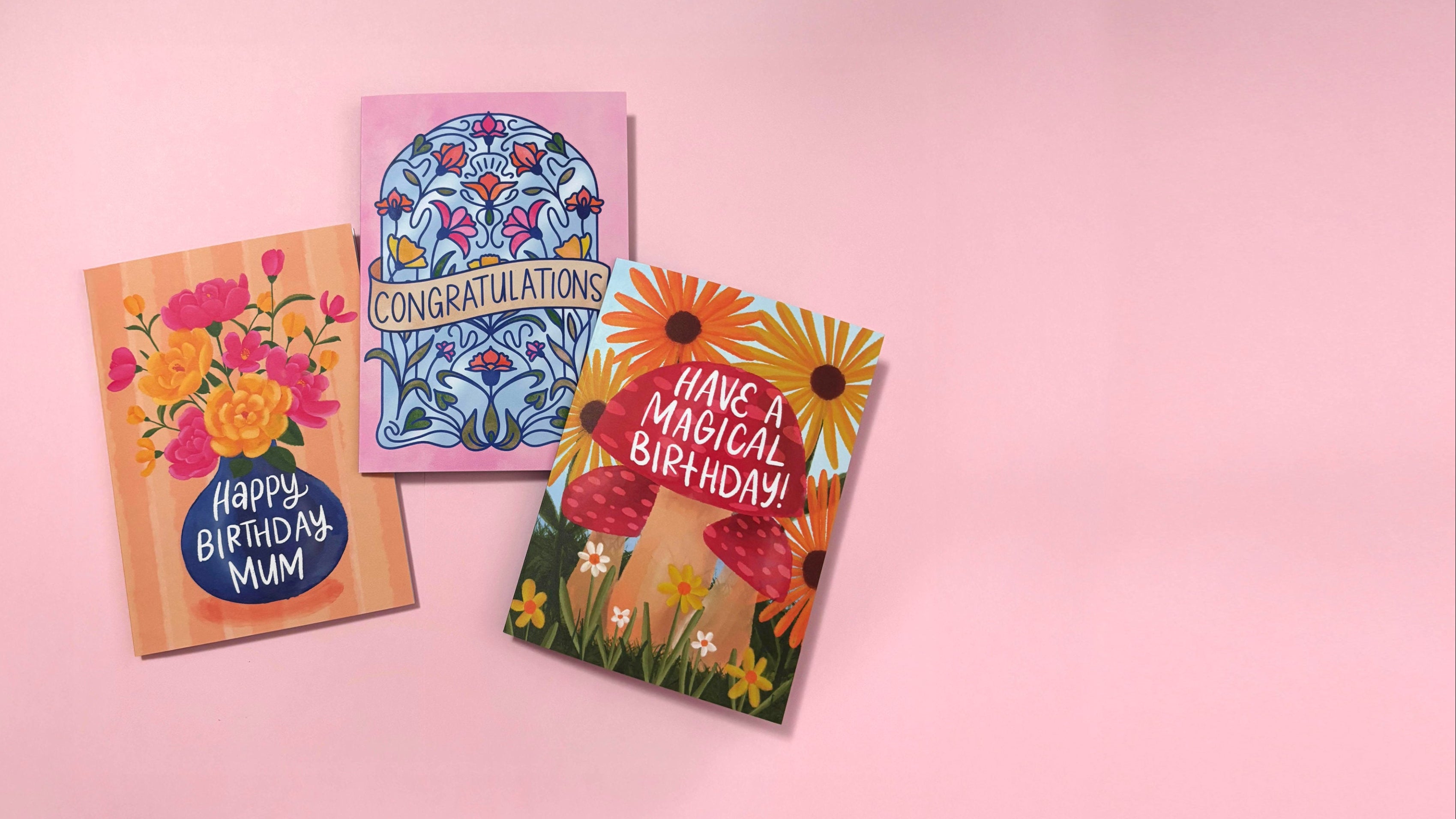 Three colourful greeting cards on a pink background