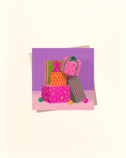 Square Christmas greeting card with light purple background and illustration of stacked Christmas presents, placed on top of a brown kraft envelope.