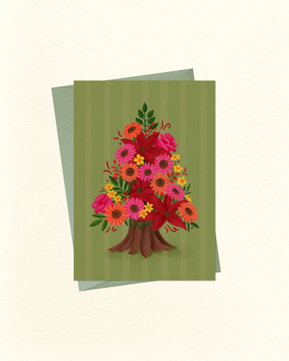 A greeting card featuring a colorful bouquet of flowers arranged in the shape of a tree, set against a striped olive green background, with a matching green envelope behind it on a cream-colored surface.