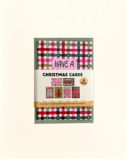 A package of 6 Christmas cards featuring festive red, green, and pink plaid patterns, shown on a light cream background.
